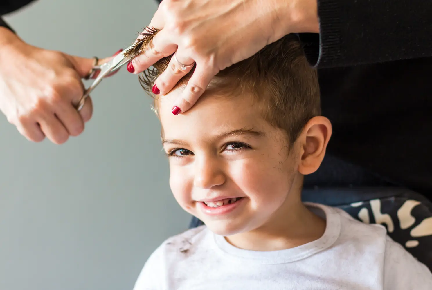 Ein lächelnder Junge mit kurzen braunen Haaren bekommt einen Haarschnitt