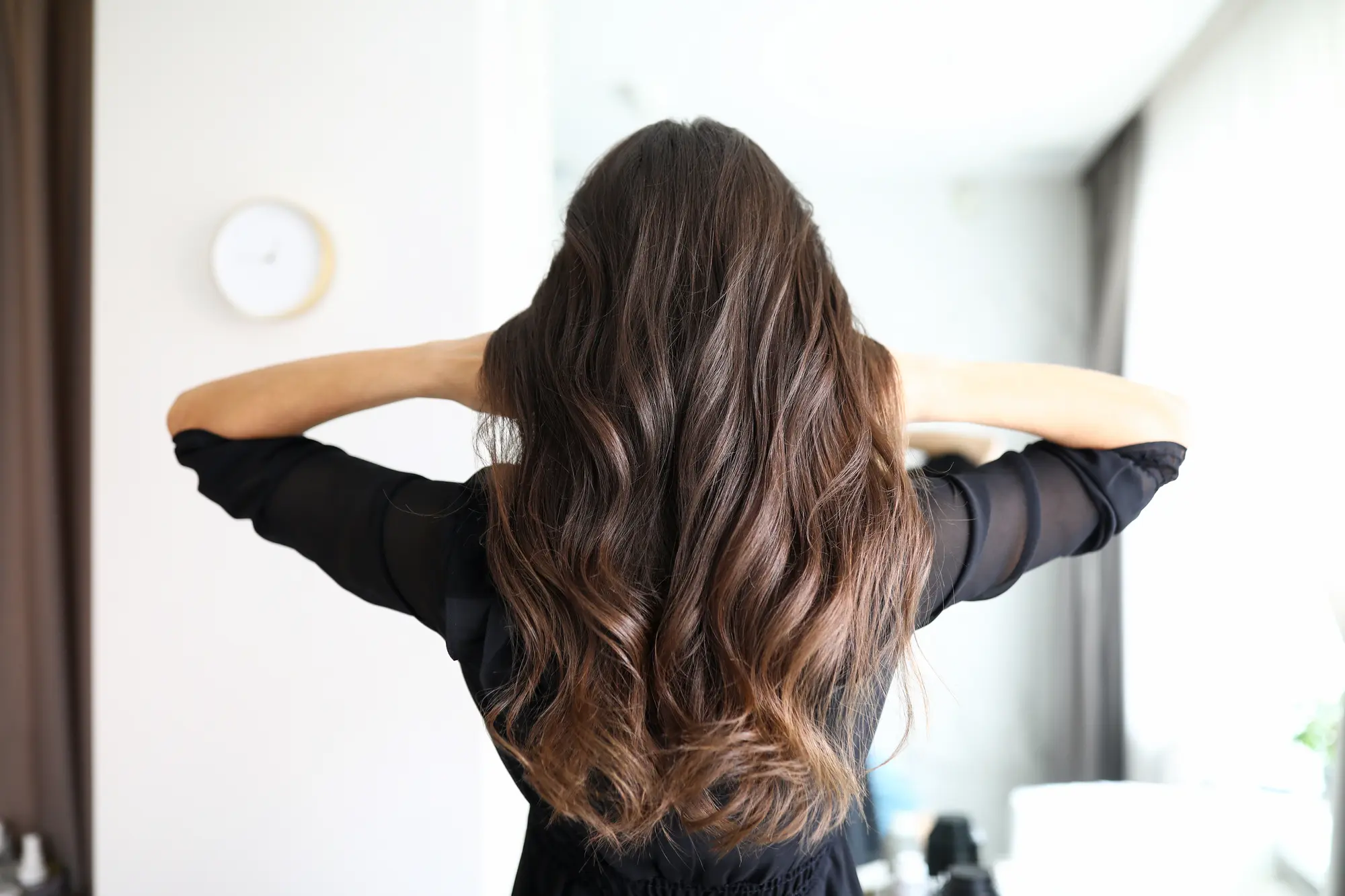 Eine Frau mit langen gewellten braunen Haaren steht in einem hellen Raum