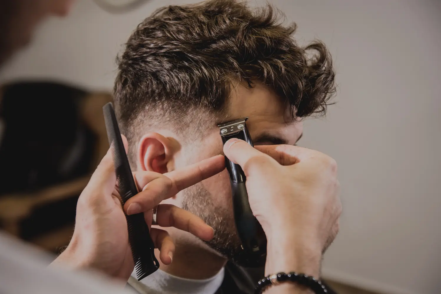 Ein junger Mann mit braunen Haaren bekommt einen frischen Haarschnitt beim Friseur